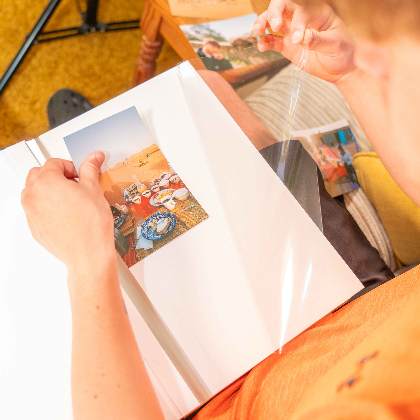 Person holding a photo album with a page showing a desert scene.