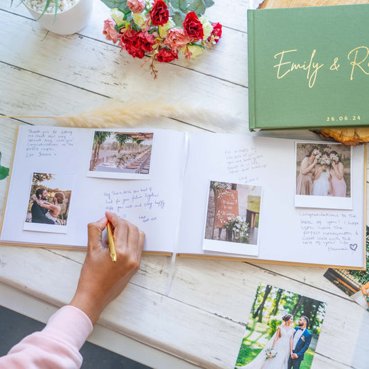 woman writing inside a wedding guest book with polaroids