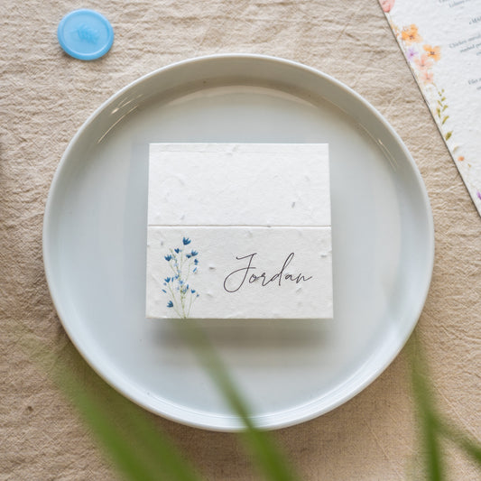 White card with 'Jordan' printed on it, featuring a floral design, placed on a white plate.
