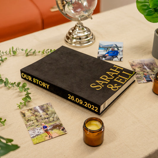 Personalized book titled 'Our Story Sarah & Ell' with photos and a candle on a table.