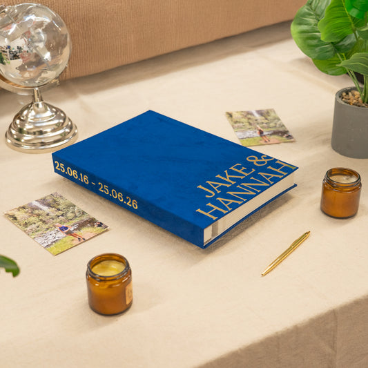 Blue book with personalized text on a table with candles and cards