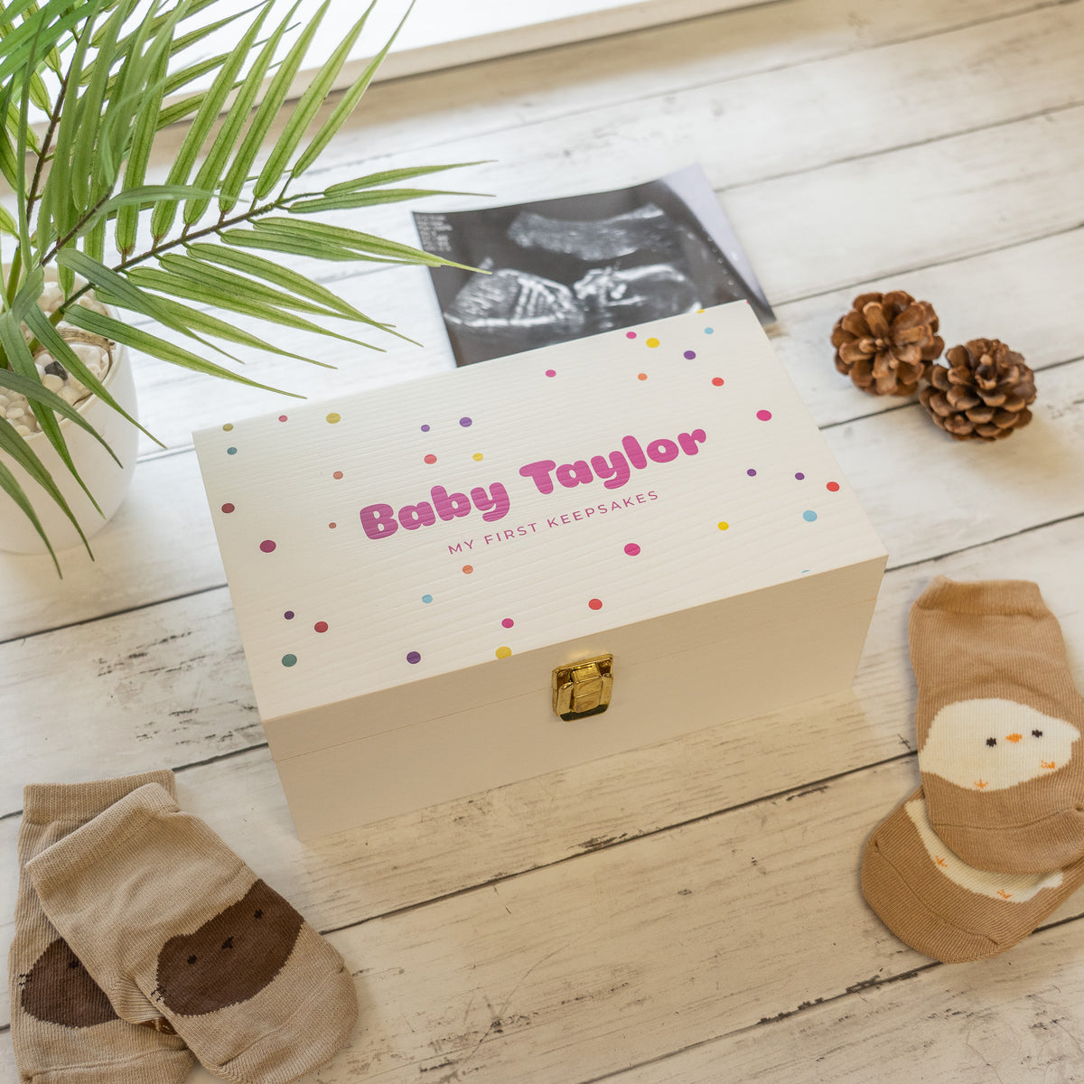 A baby white keepsake box surrounded by baby items like baby socks and an ultrasound