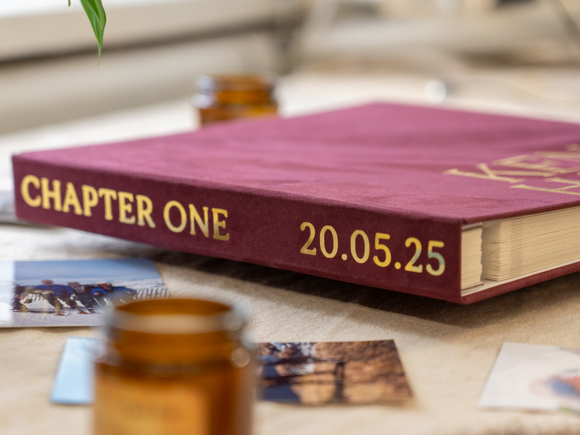 A maroon hardcover photo book with gold foil lettering reading 'CHAPTER ONE' and the date '20.05.