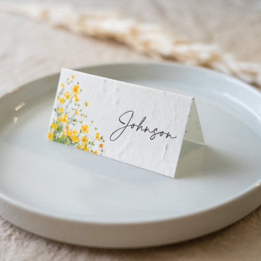 Place card with yellow floral design and 'Johnson' text on a white plate.