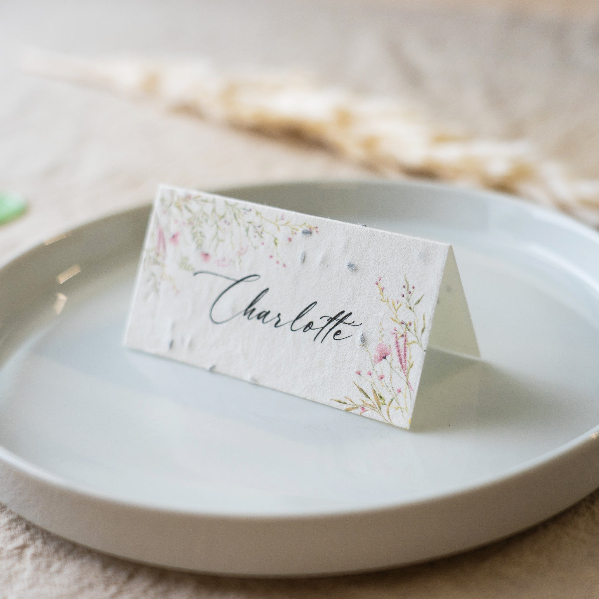 Floral place card with 'Charlotte' on a white plate
