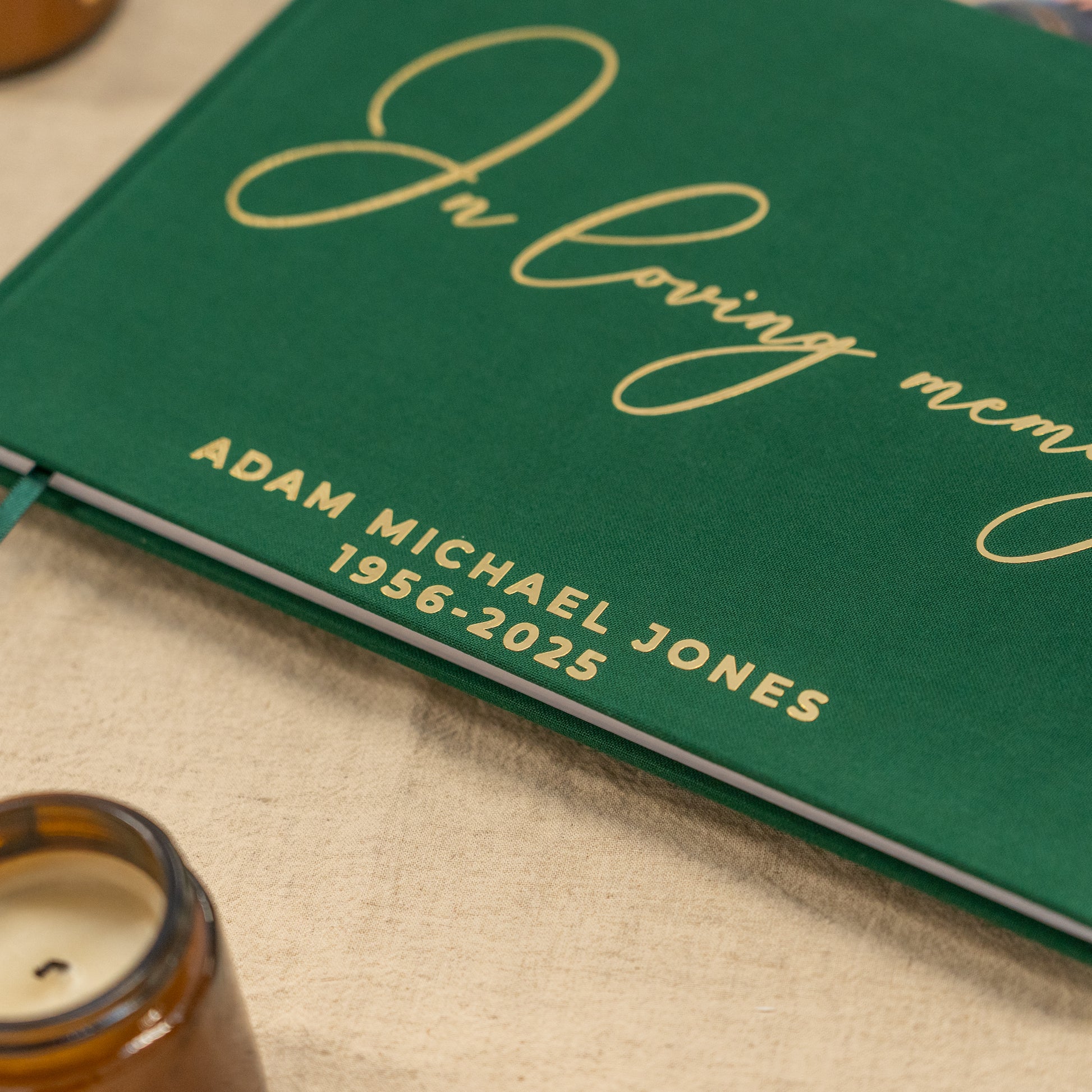 Green condolence book with gold text on a beige surface