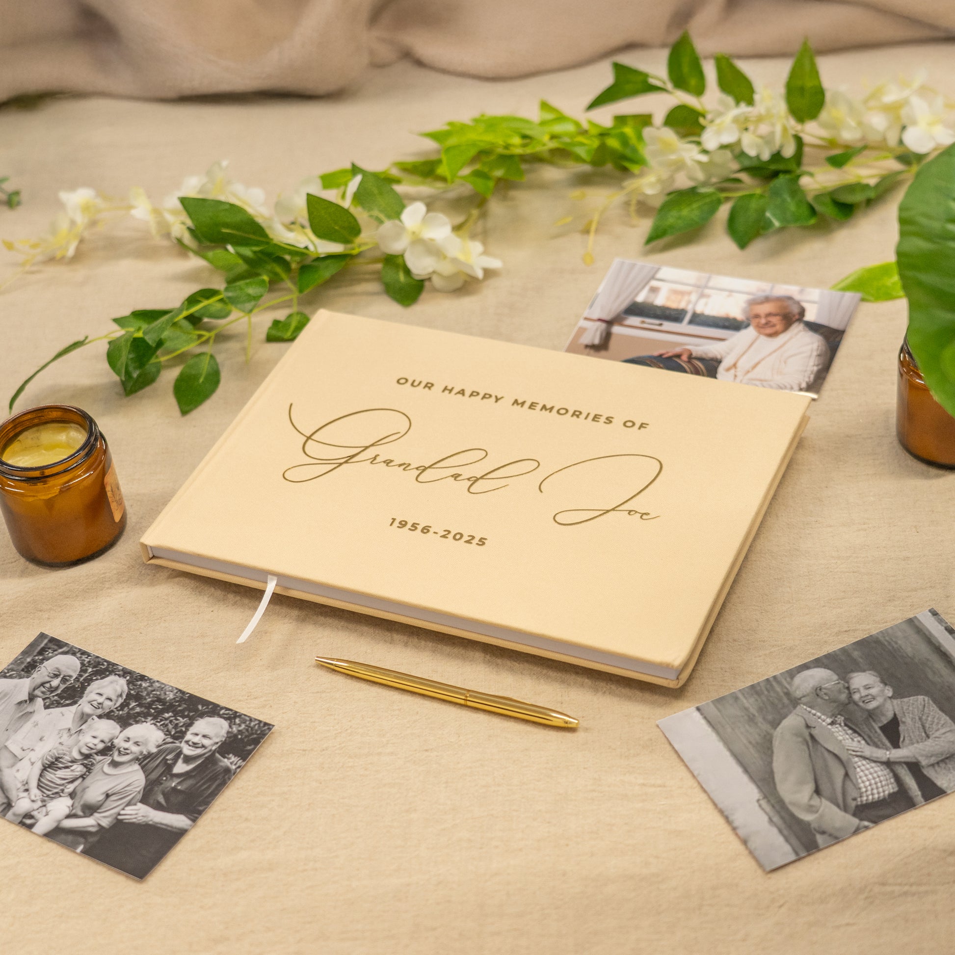 Memorial book with photos and a pen on a table with flowers and candles