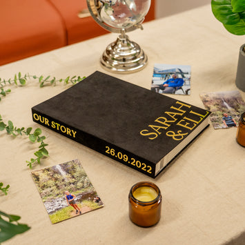 Personalized book titled 'Our Story Sarah & Ell' with photos and a candle on a table.