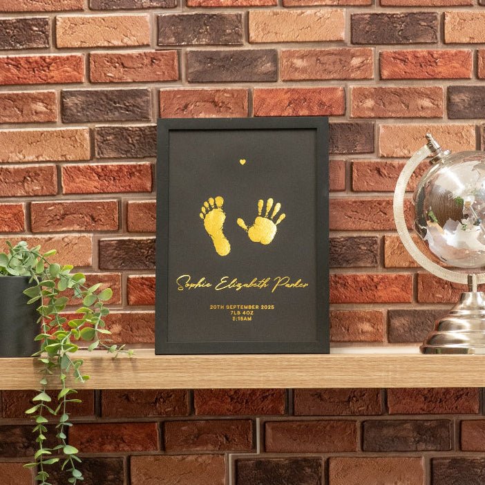 Framed artwork with footprints on a wooden shelf against a brick wall.