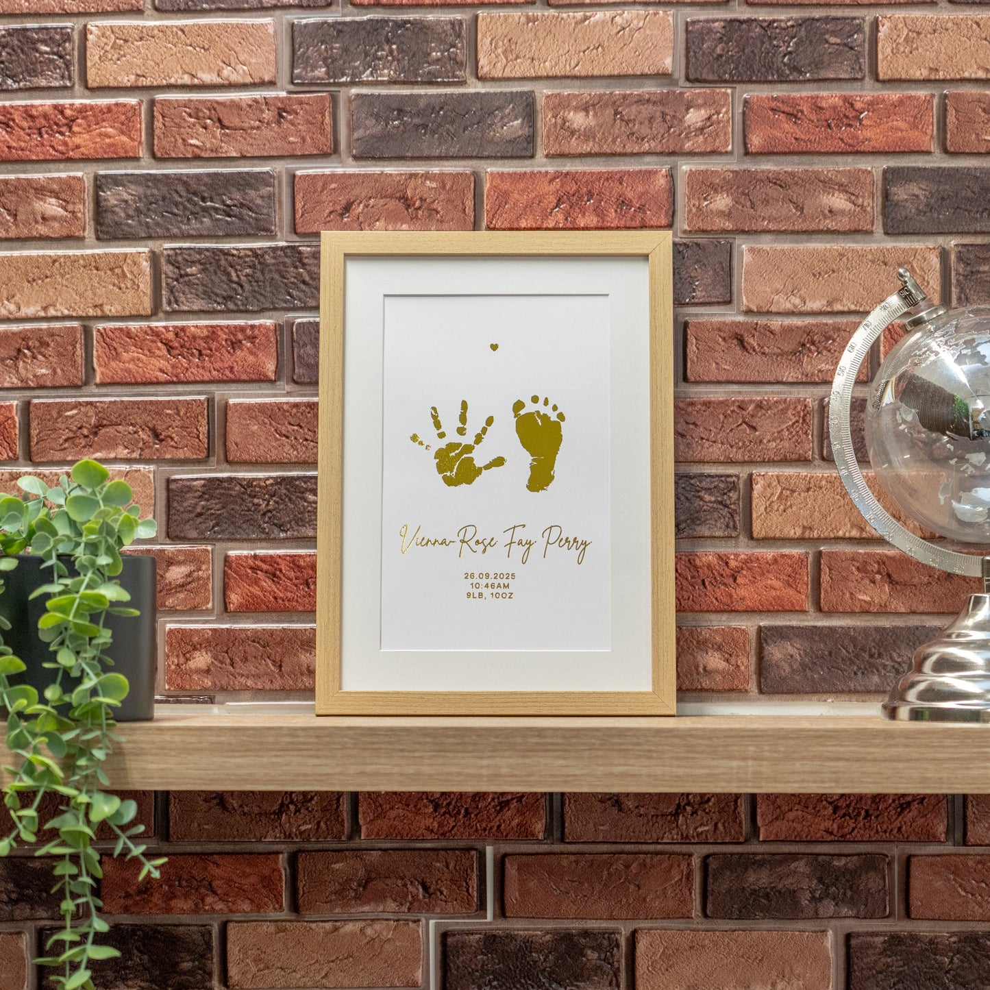 Framed artwork with hand and footprints on a brick wall background