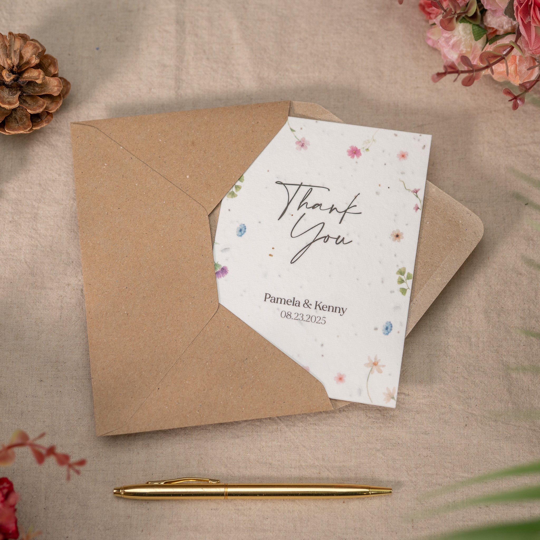 Thank you card with floral design and brown envelope on a textured surface with decorative elements.