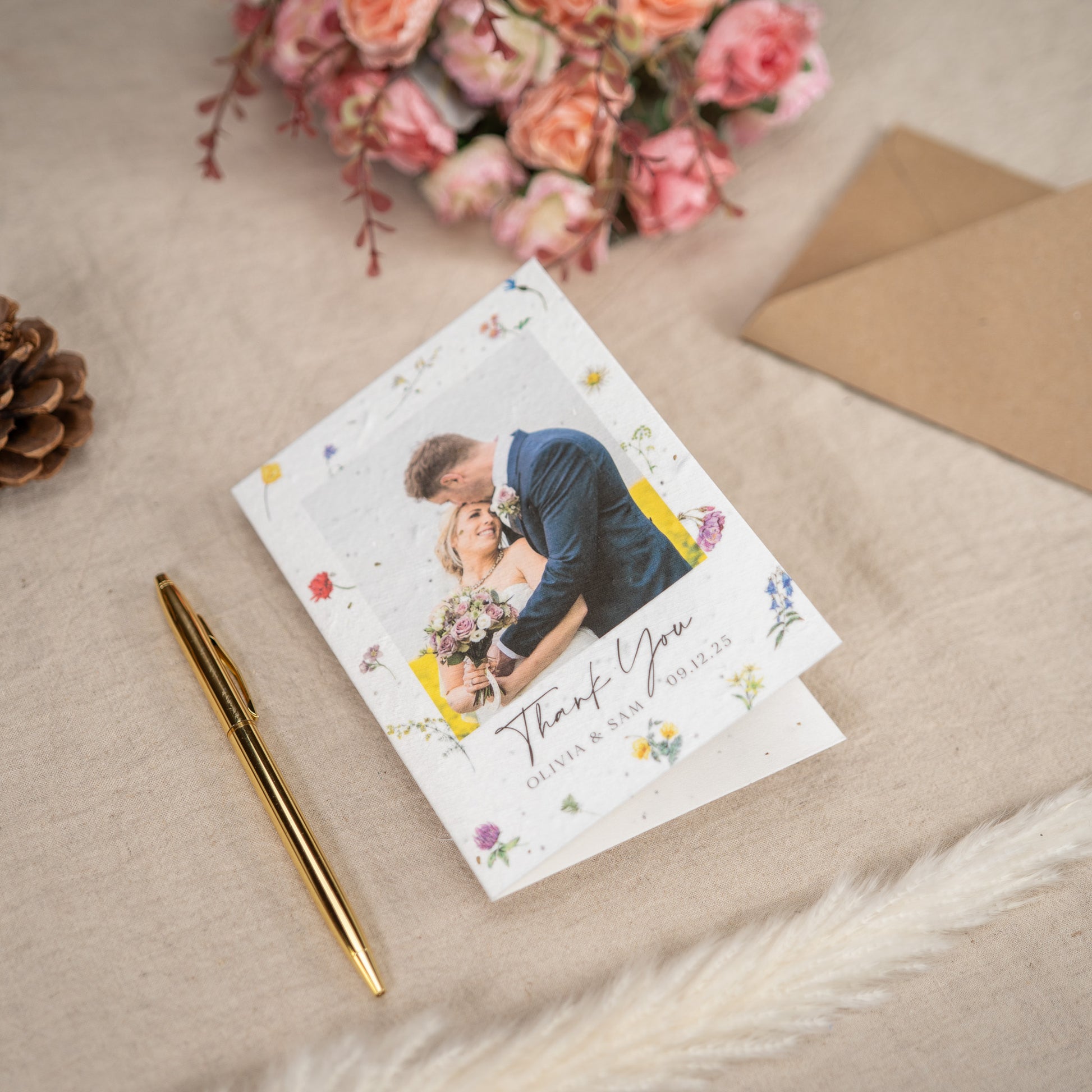 Greeting card with a couple and flowers, pen, and envelope on a textured surface.