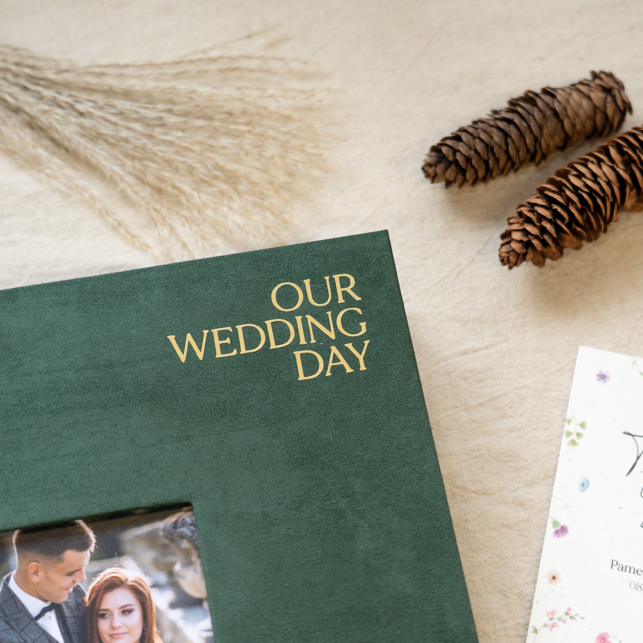 Green photo album titled 'Our Wedding Day' on a wooden surface with decorative elements.