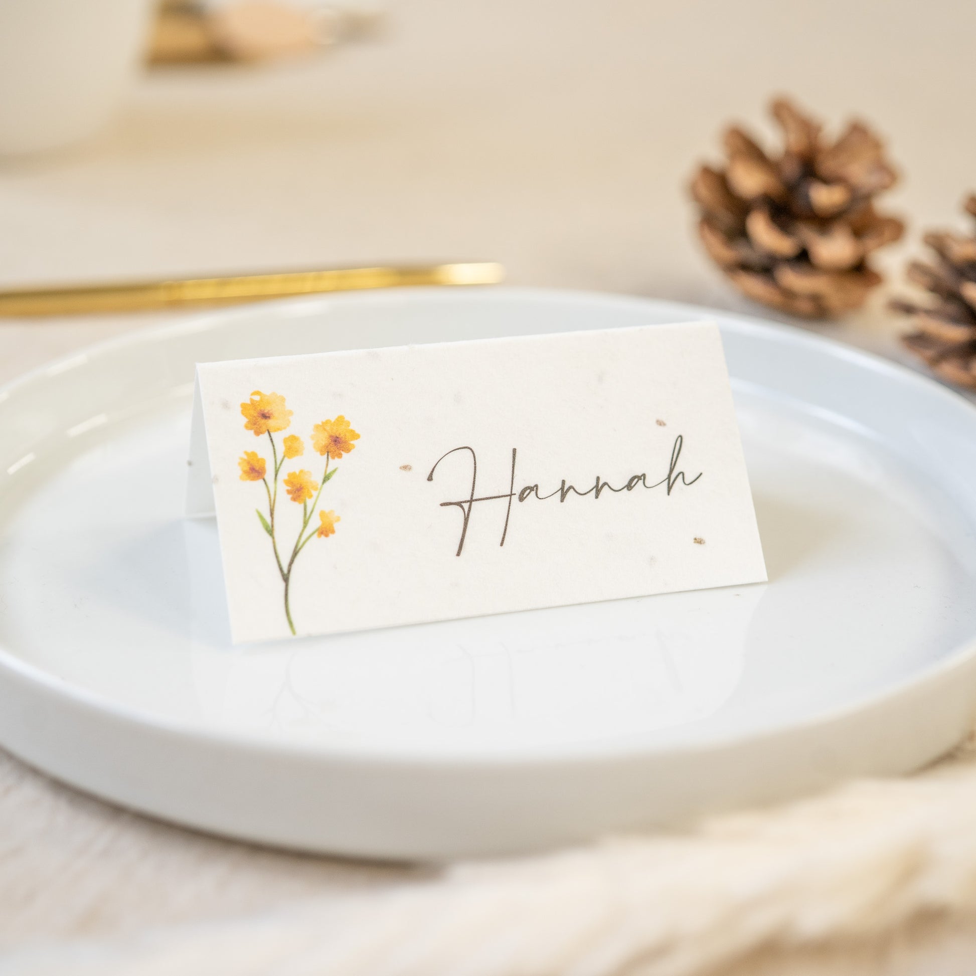 Place card with floral design and 'Hannah' text on a white plate with gold rim.