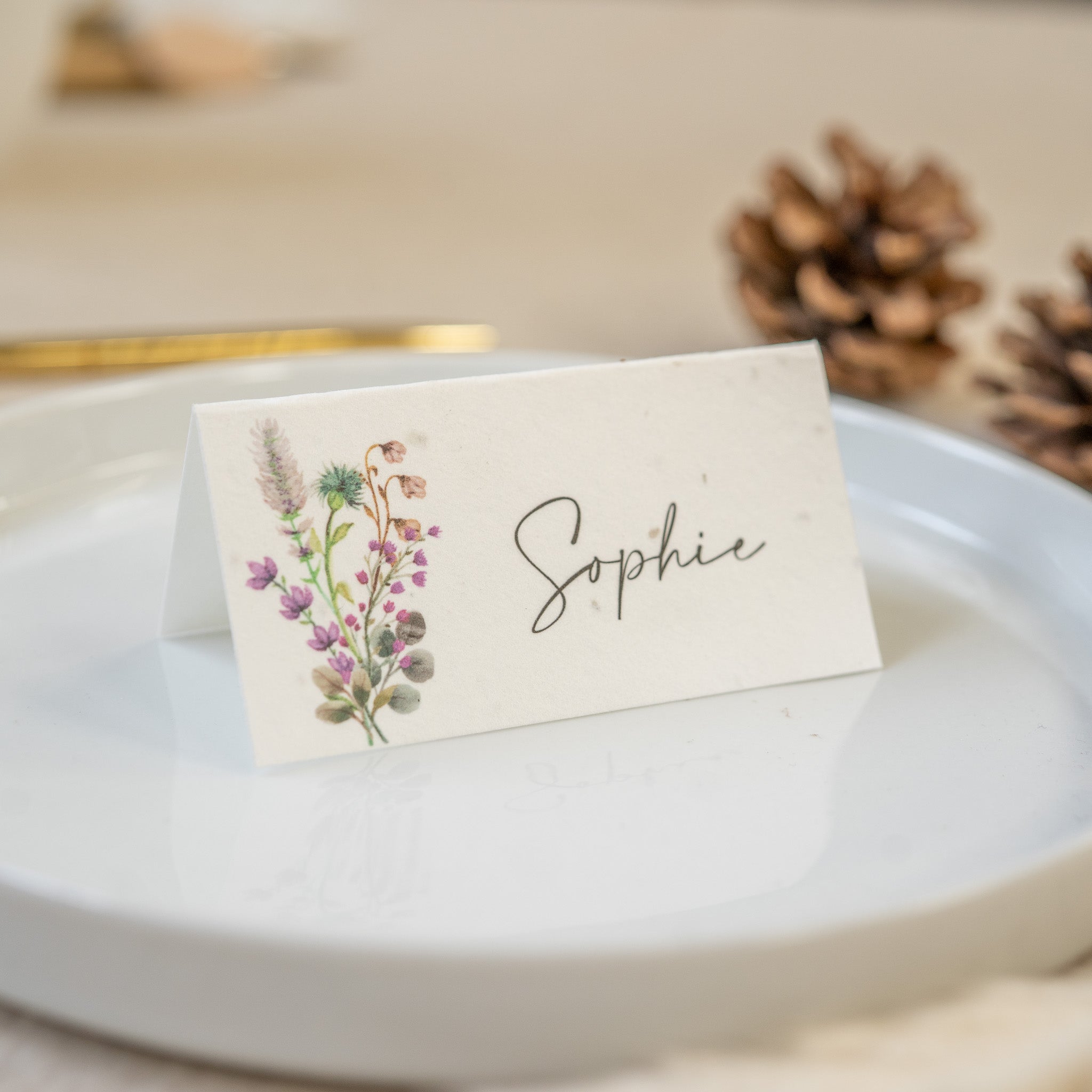Place card with floral design and 'Sophie' text on a white plate.