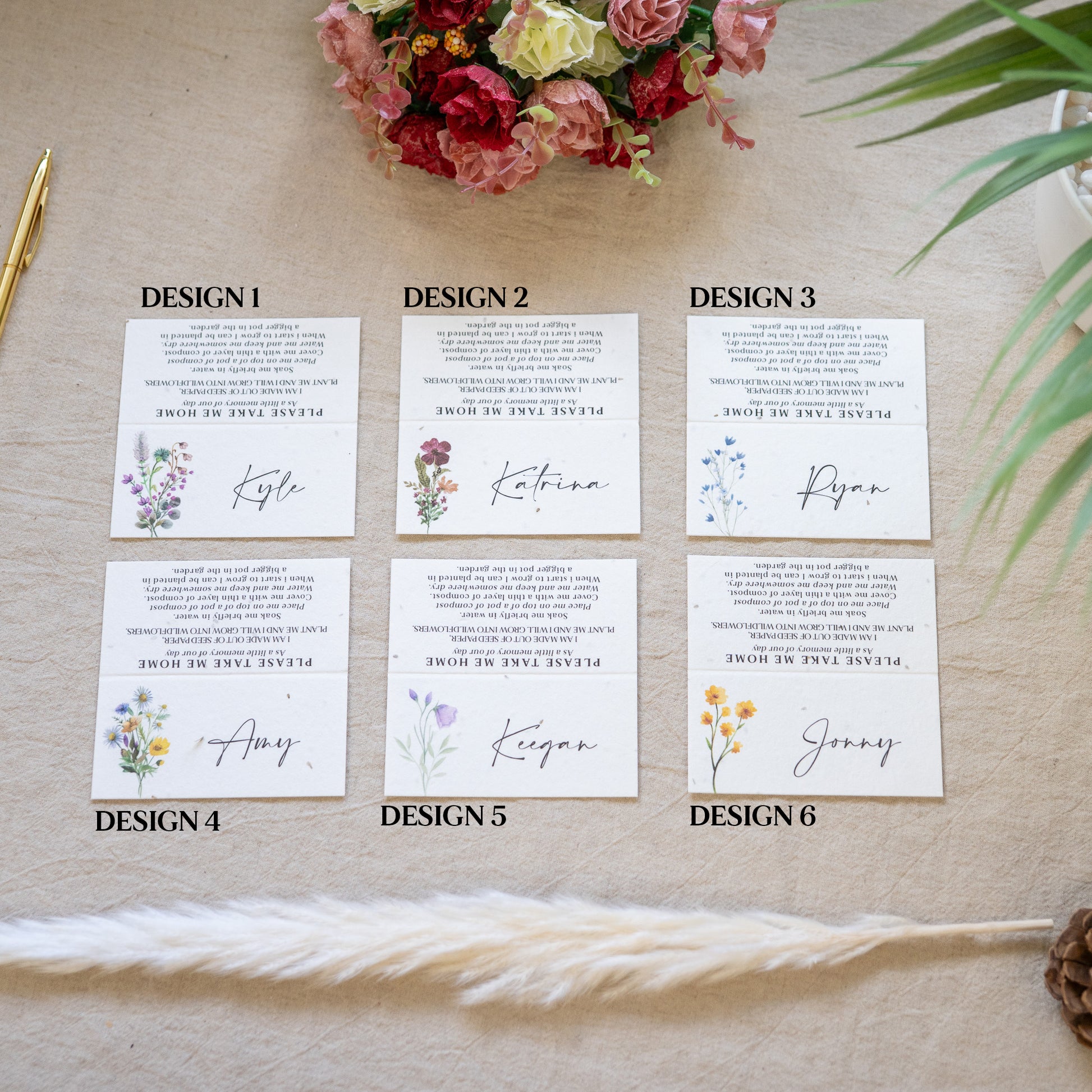 Six floral design name cards on a textured surface with flowers and a feather.