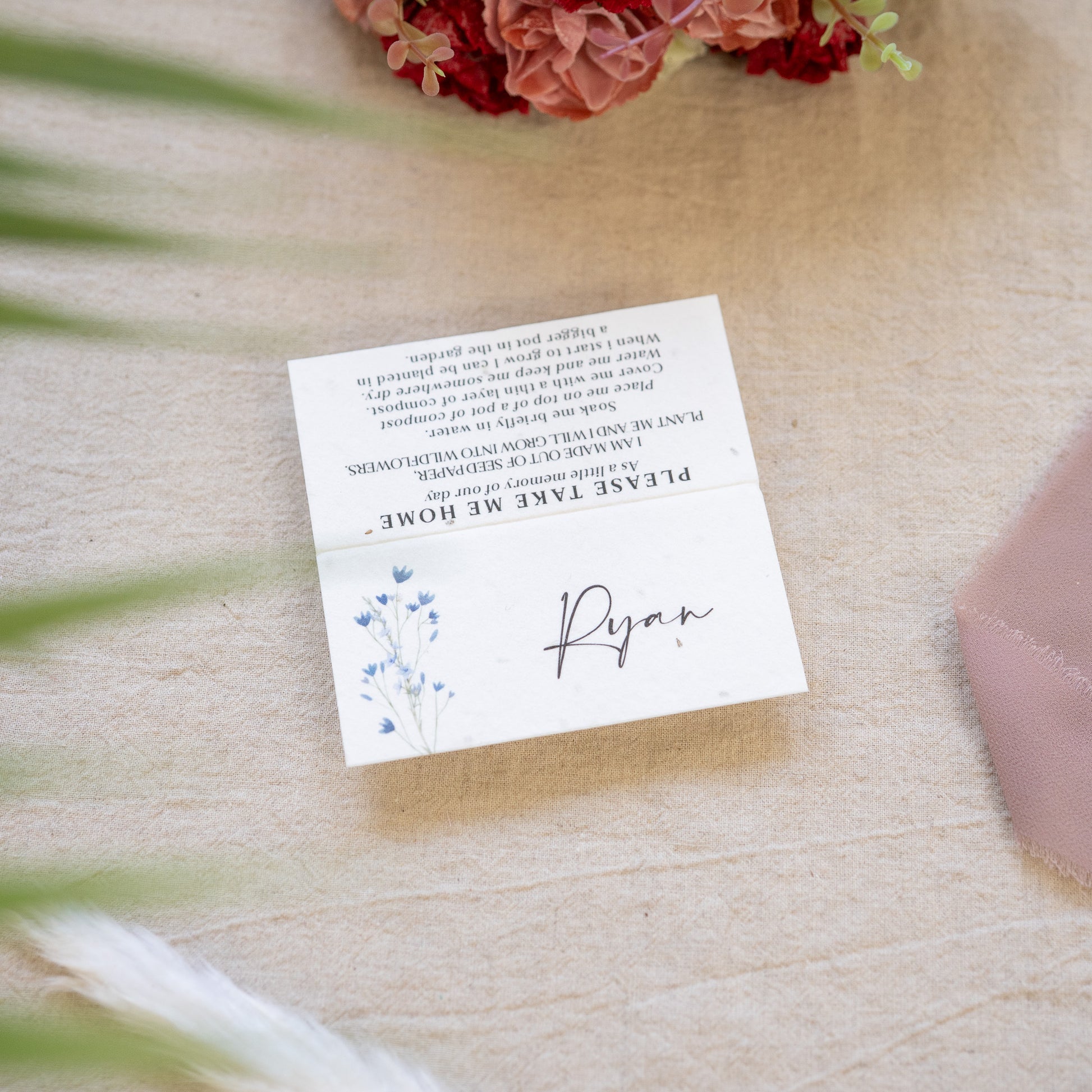 White card with text and floral design on a textured surface with flowers in the background