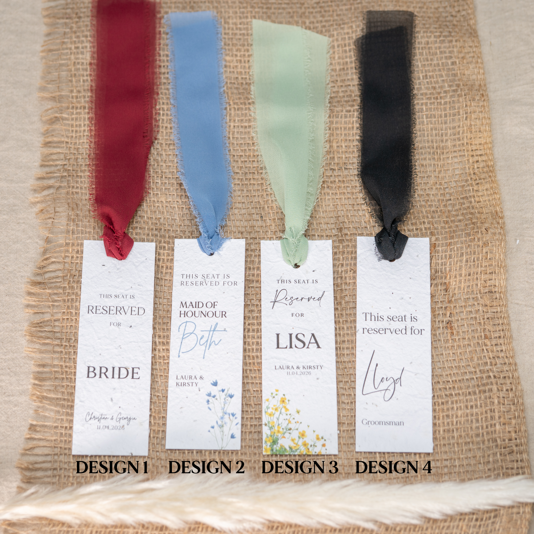 Four wedding seat reservation cards with ribbons on a textured fabric background