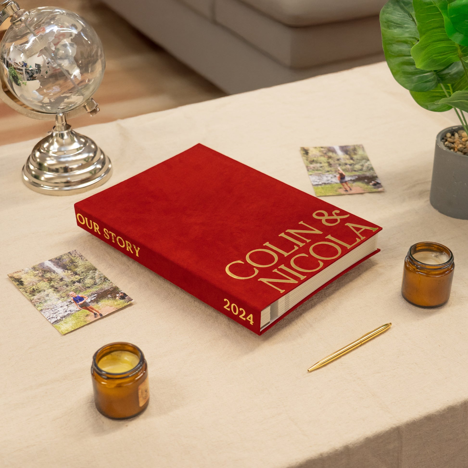 Red book titled 'Our Story Colin & Nicola 2024' on a table with candles and cards.