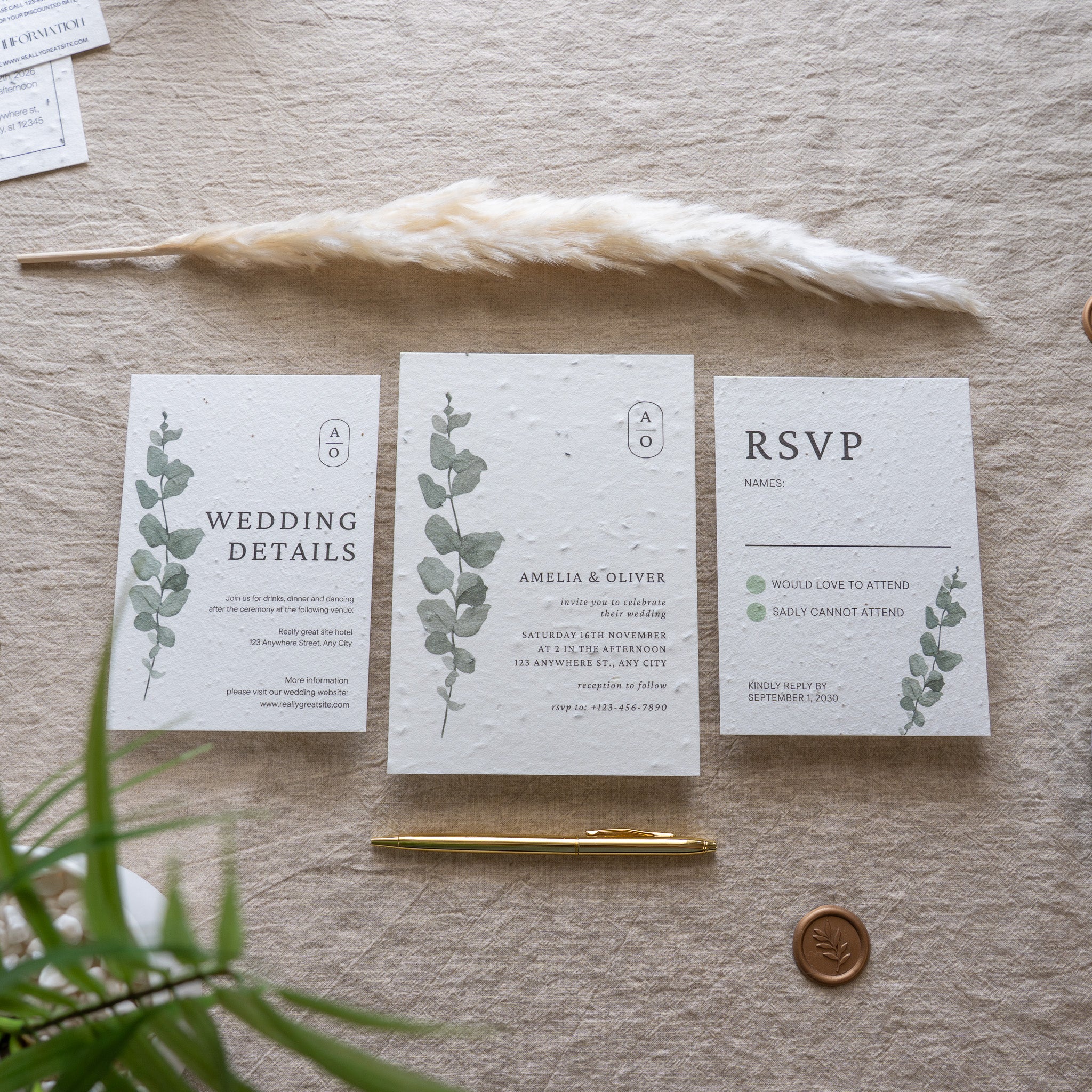 Wedding invitation set with 'RSVP' card, pen, and dried plant on a textured surface
