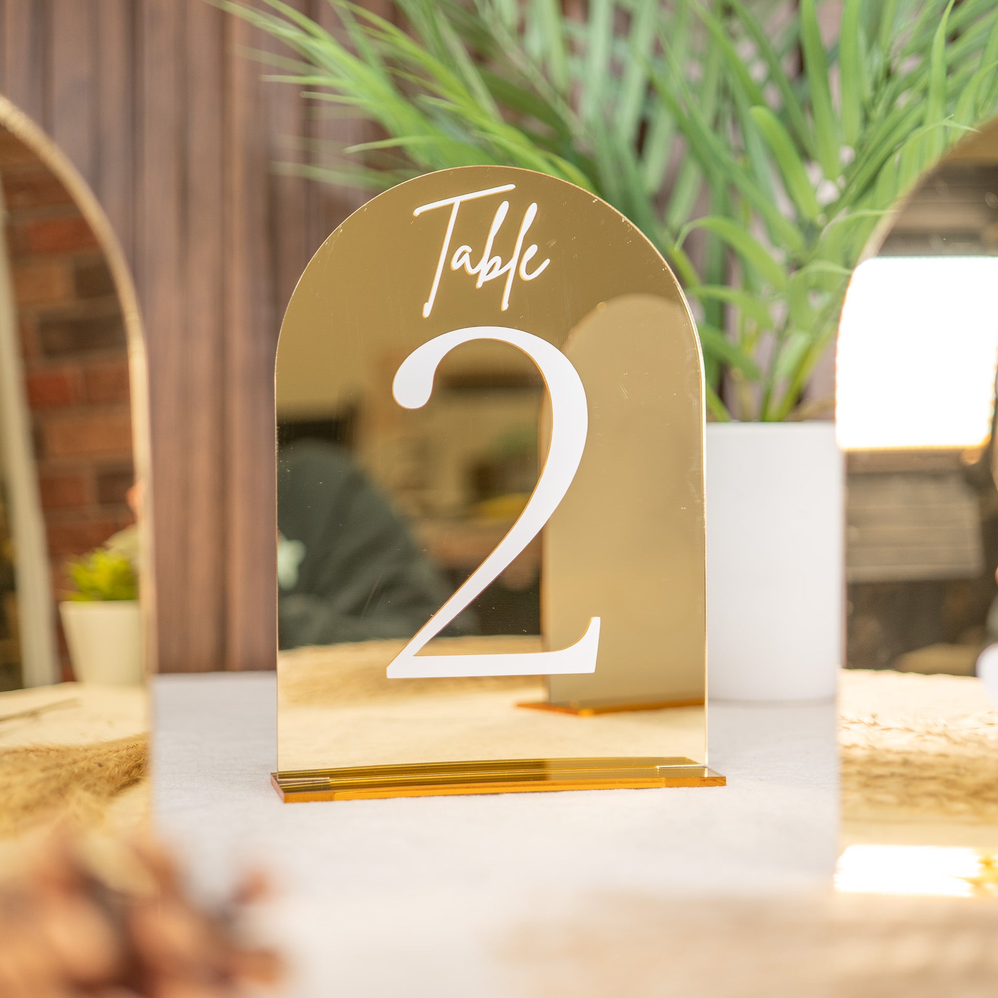 Gold table number '2' on a white surface with a blurred background