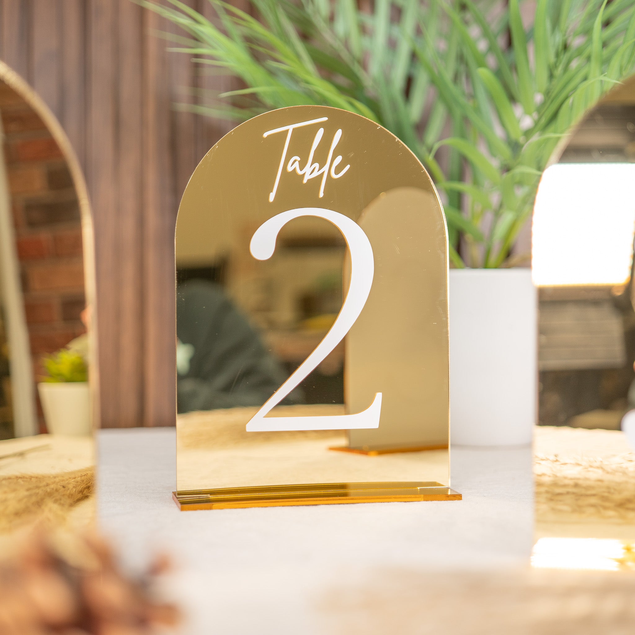Gold table number '2' on a white surface with a blurred background