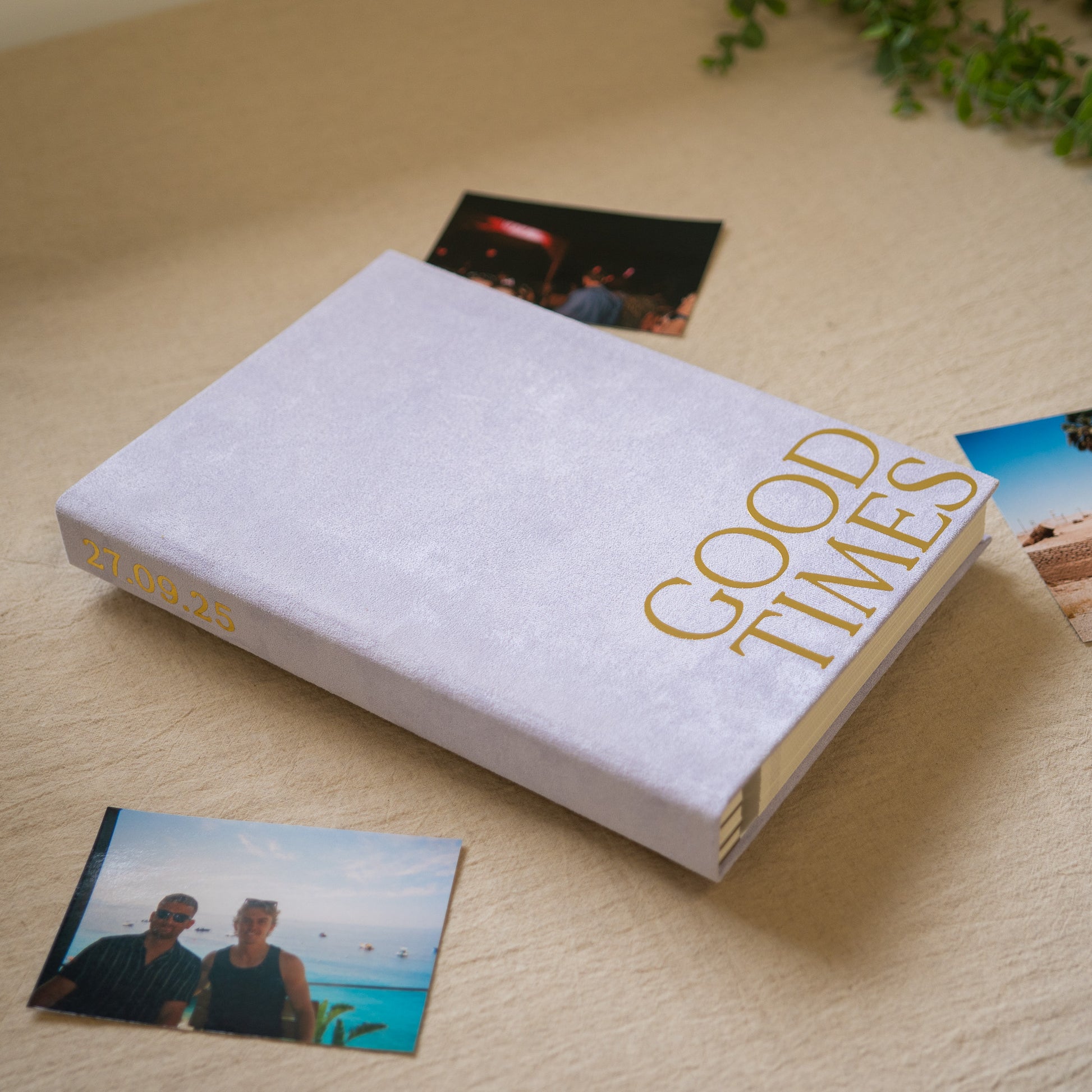 A light purple book with good times written in chrome gold. Surrounded by printed photographs 