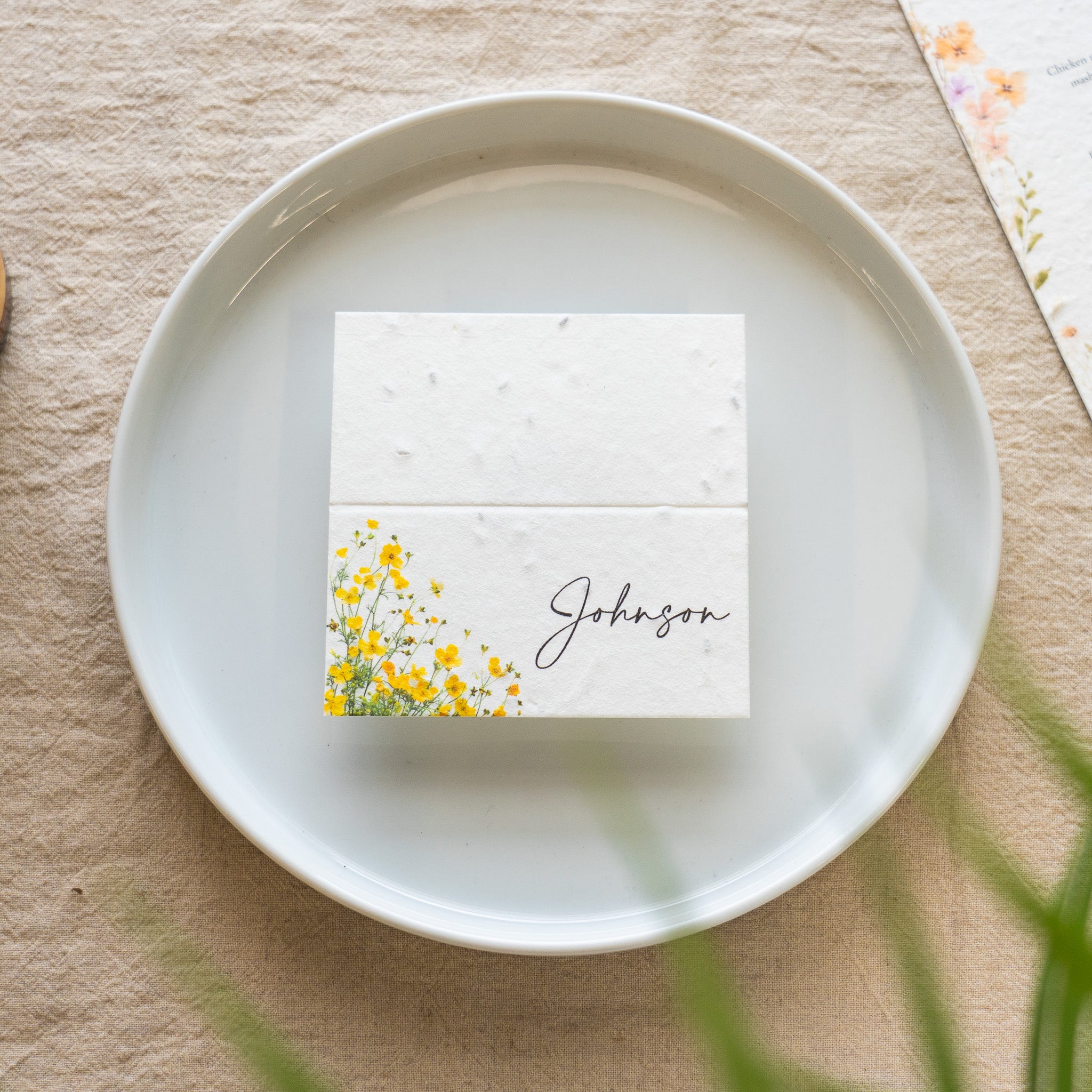 White square card with floral design and 'Johnson' text on a white plate