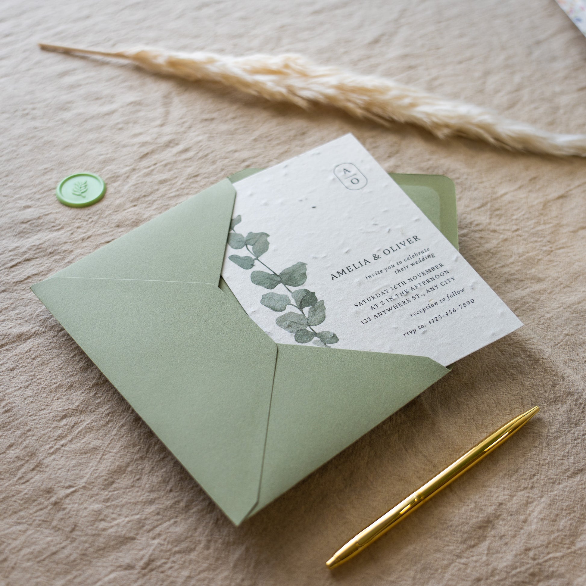 Green envelope with a matching card featuring eucalyptus leaves on a beige surface.