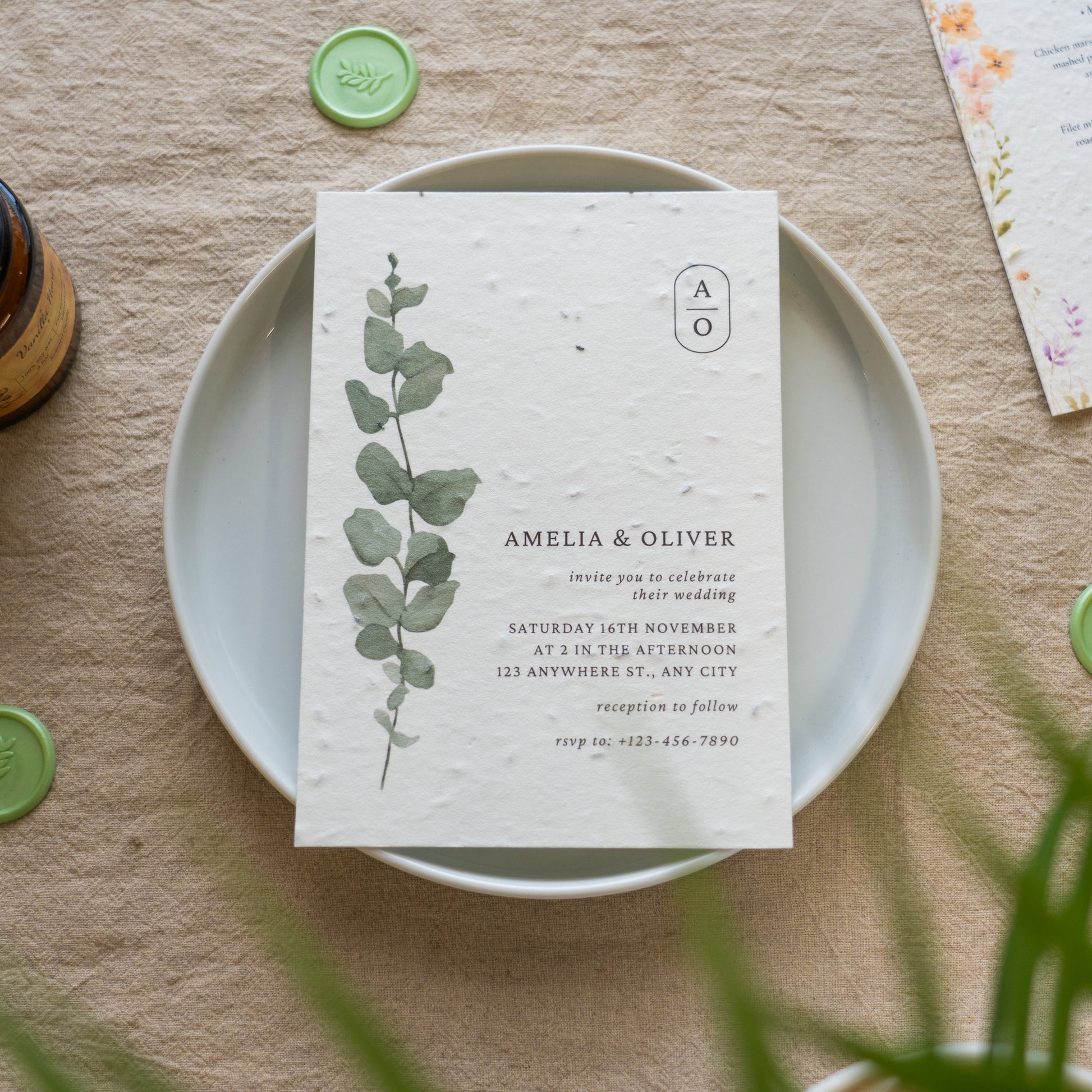 Wedding invitation card with eucalyptus design on a white plate