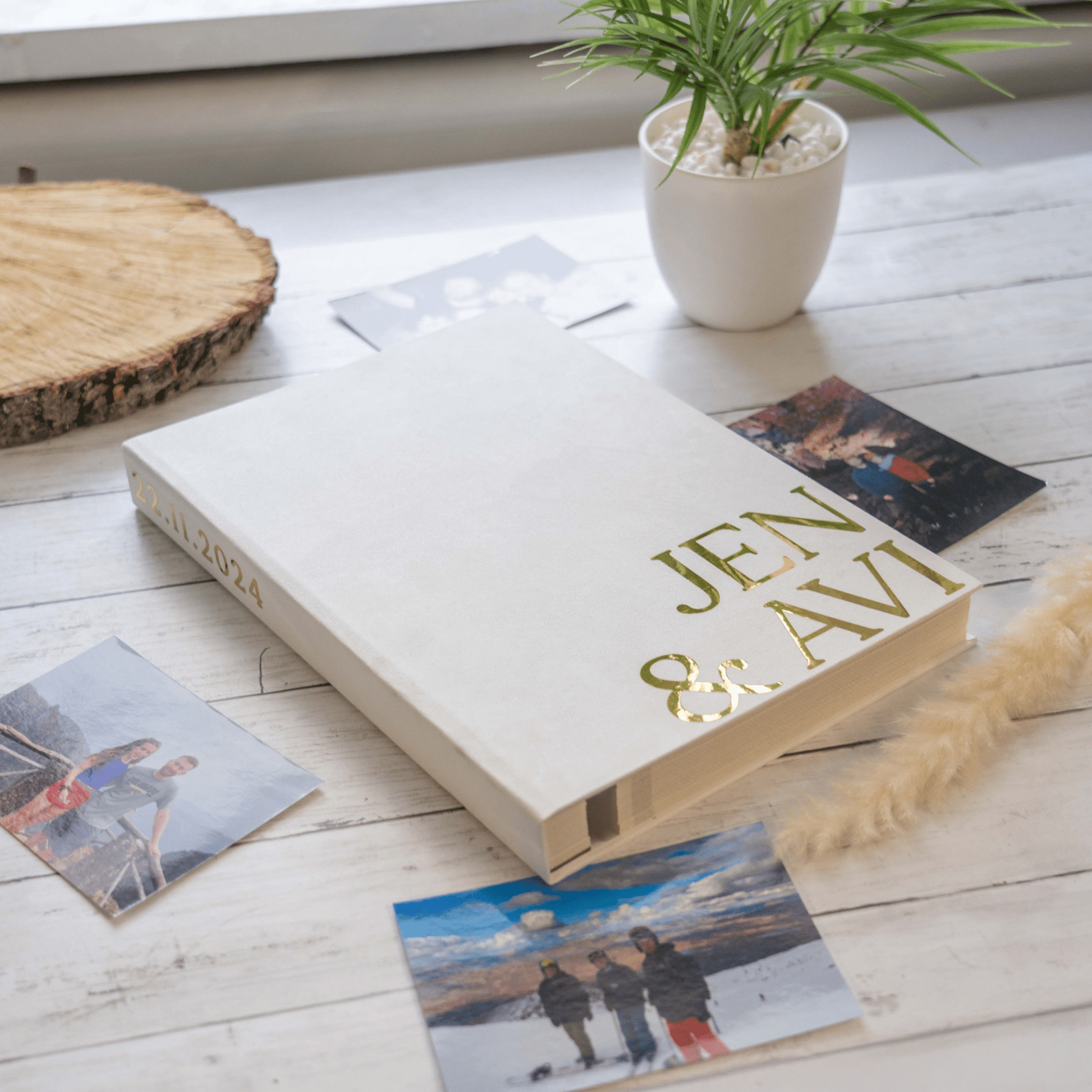 Album with 'JEN & AVI' on a wooden surface with scattered photos